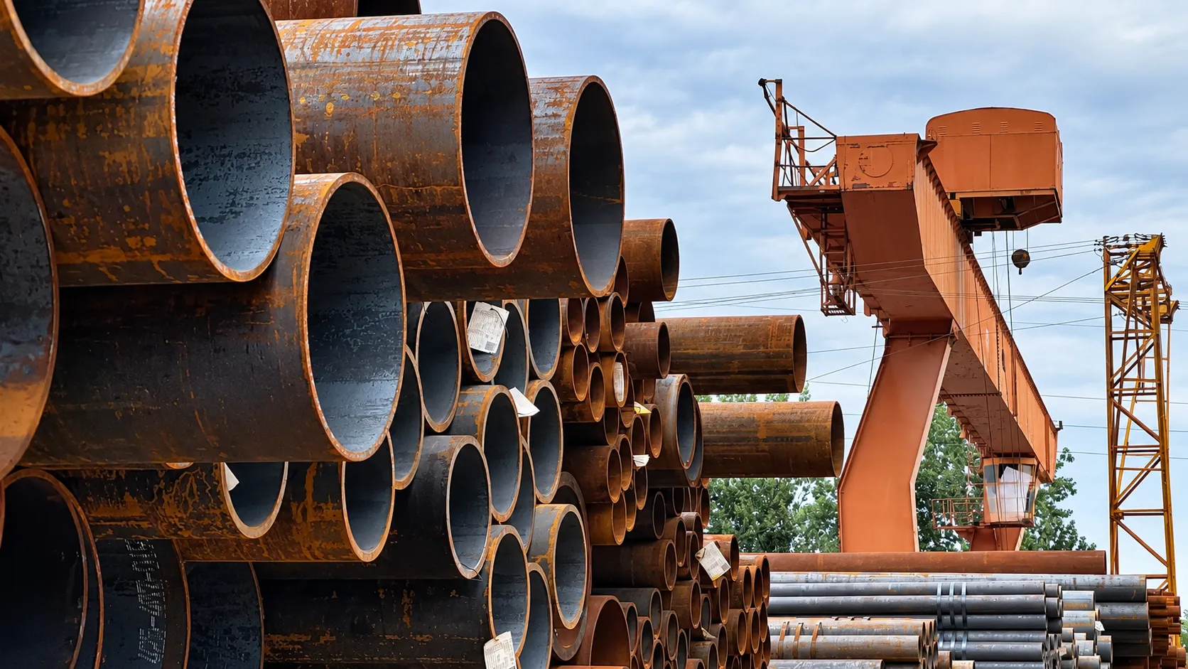Stacked steel pipes and gantry crane in a fabrication yard